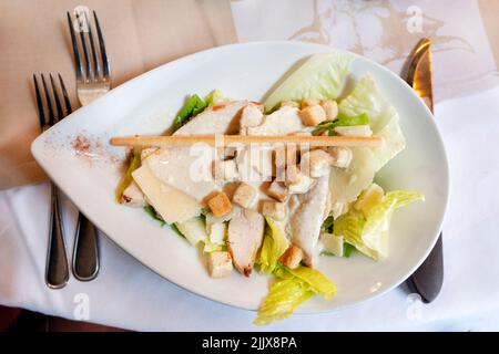 Une salade César classique, joliment présentée, servie à une table de restaurant. La salade est recouverte d'une sauce crémeuse et de croûtons Banque D'Images