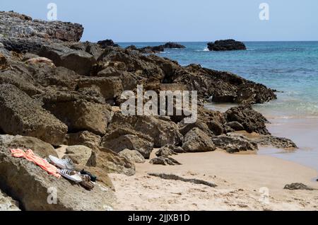 Vila do Bispo, Portugal. 17th juillet 2022. Des chaussures de bain se trouvent sur un rocher près de l'eau à la plage 'Praia da Ingrina' dans l'Algarve. Crédit : Viola Lopes/dpa/Alamy Live News Banque D'Images