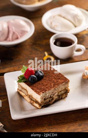 Dessert tiramisu servi sur une assiette blanche avec espresso Banque D'Images