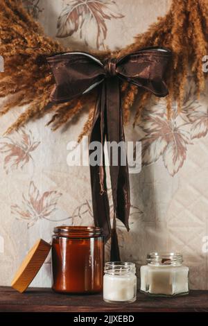 Bougies parfumées à l'intérieur. Intérieur aux couleurs laiteuses et brunes. Bougies dans un verre Banque D'Images