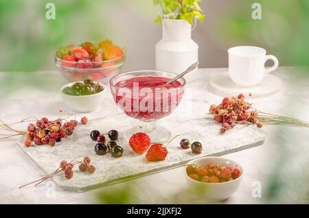 Confiture de baies de fraises, raisins de Corinthe noirs dans un bol sur fond clair. Banque D'Images