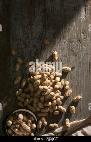 pile d'arachides non pelées sur un fond en bois avec une vieille tasse, également connue sous le nom de arachide, goober, pindar ou noix de singe, prise directement d'en haut Banque D'Images