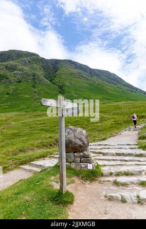 Ben Nevis montagne Ecosse, une femme de randonnée dans sa cinquantaine commence la randonnée en solo de Ben Nevis montagne en Ecosse, été 2022, Royaume-Uni avec sac à dos et poteaux Banque D'Images