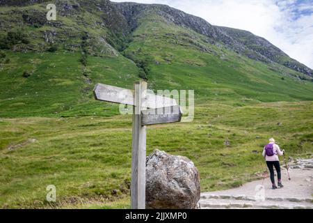 Ben Nevis montagne Ecosse, une femme de randonnée dans sa cinquantaine commence la randonnée en solo de Ben Nevis montagne en Ecosse, été 2022, Royaume-Uni avec sac à dos et poteaux Banque D'Images