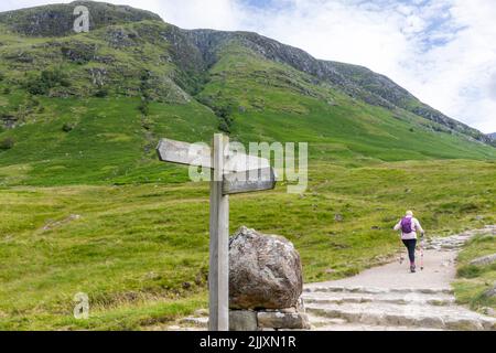 Ben Nevis montagne Ecosse, une femme de randonnée dans sa cinquantaine commence la randonnée en solo de Ben Nevis montagne en Ecosse, été 2022, Royaume-Uni avec sac à dos et poteaux Banque D'Images