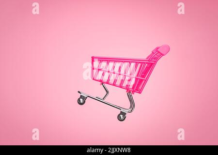 Pink shopping Trolley concept de supermarché. Chariot vide isolé arrière-plan rose. Boutique de chariots de vente en ligne. Ventes concept rose jouet Banque D'Images