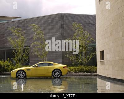 Un Aston Martin Vantage jaune Sunburst exposé dans le douve à l'extérieur du siège de AM à Gaydon, Warwickshire, avec Gaydon Design Studio en arrière-plan Banque D'Images