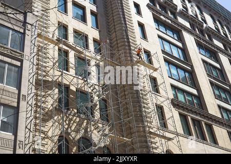 New York, NY, Etats-Unis - 27 juillet 2022 : deux hommes sont montrés érigeant des échafaudages métalliques sur le côté d'un immeuble de Manhattan à l'ouest 16th St et Fifth Avenu Banque D'Images