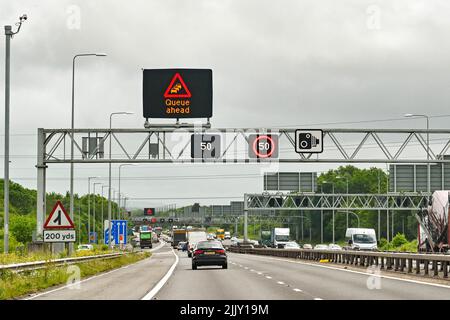 Bristol, Angleterre - Mai 2022: Trafic approchant d'une file d'attente sur l'autoroute M4 près de Bristol, avec des panneaux d'avertissement de limite de vitesse au-dessus. Banque D'Images