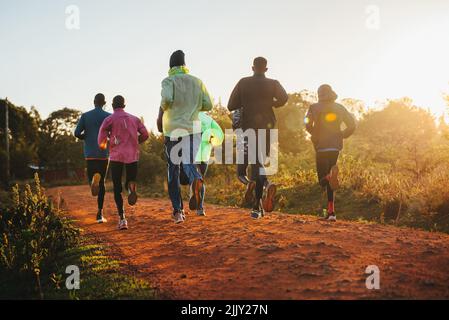 Entraînement matinal. Au Kenya. Les coureurs de marathon en sol rouge s'entraînent à la lumière du soleil levant. Motivation à bouger. Course d'endurance, athlétique Banque D'Images