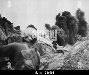 Le char à flammes brûle les JAP de l'armée américaine : un soldat américain (Foreground) tient son fusil prêt à se lever pendant qu'un char à flammes de la division d'infanterie de l'armée américaine 96th brûle les JAP se cachant dans des trous le long d'une route en contrebas sur une crête âprement disputée de « Big Apple » du sud d'Okinawa. 21 juin 1945. (Photo par AP Wirephoto). Banque D'Images
