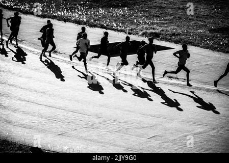 Formation de groupe au Kenya. Un grand groupe de coureurs kenyans se prépare à la course. Les coureurs professionnels d'endurance et de marathon courent sur le sol rouge o Banque D'Images