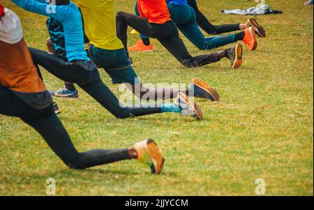 Étirement et échauffement des coureurs africains. Les joggeurs et les coureurs de marathon se préparent à courir sur l'herbe verte. Photo de la formation au Kenya Banque D'Images