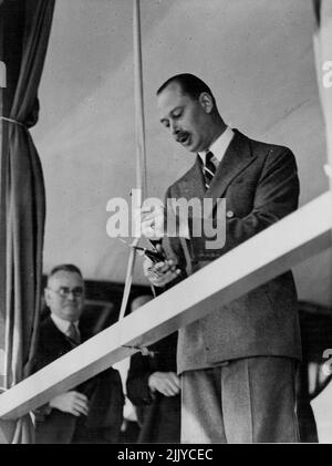 H.R.H. le duc de Gloucester coupe le ruban pour libérer le premier avion à voler la route aérienne régulière de l'Australie de l'Angleterre avec les ciseaux d'or uniques qui lui ont été présentés pour le but par le premier ministre de tuile. Le point culminant de la cérémonie à l'aérodrome d'Archerfield hier matin (lundi). 17 décembre 1934. Banque D'Images