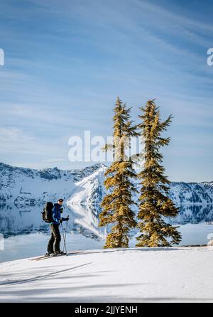 Le skieur prend vue sur Crater Lake et deux pins en hiver. Banque D'Images