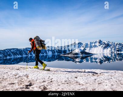 Skieur avec de grands skis le long du paisible lac Crater, Oregon Banque D'Images