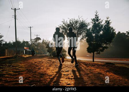 Silhouette de coureurs à l'entraînement du matin au Kenya. Les Africains s'entraînent sur les routes rouges de la ville d'iten. Préparation à la course pour les courses de marathon Banque D'Images