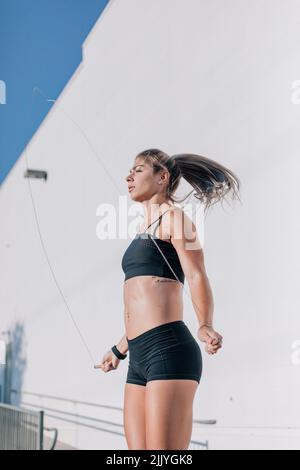 Femme portant noir faisant l'entraînement jumpprope crossfit à l'extérieur en m Banque D'Images