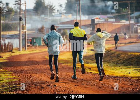 Entraînement matinal. Au Kenya. Les coureurs de marathon en sol rouge s'entraînent à la lumière du soleil levant. Motivation à bouger. Course d'endurance, athlétique Banque D'Images