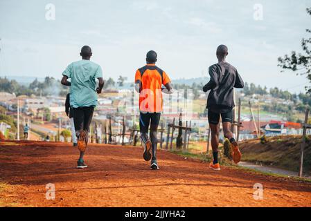 Entraînement matinal. Au Kenya. Les coureurs de marathon en sol rouge s'entraînent à la lumière du soleil levant. Motivation à bouger. Course d'endurance, athlétique Banque D'Images