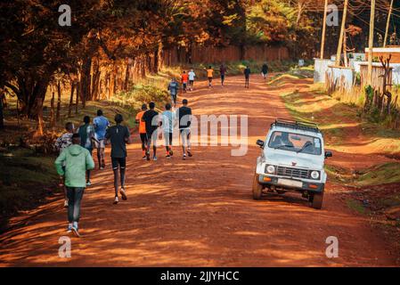 Formation de groupe au Kenya. Un grand groupe de coureurs kenyans se prépare à la course. Les coureurs professionnels d'endurance et de marathon courent sur le sol rouge o Banque D'Images