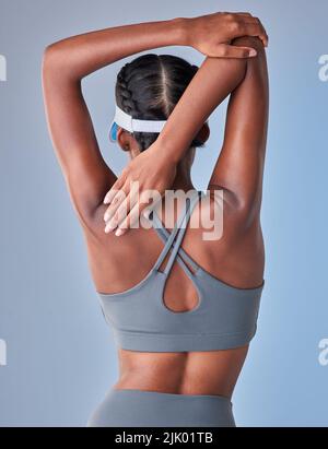 Un bon étirement va un long chemin. Photo studio d'une jeune femme en forme s'étendant sur un fond gris. Banque D'Images