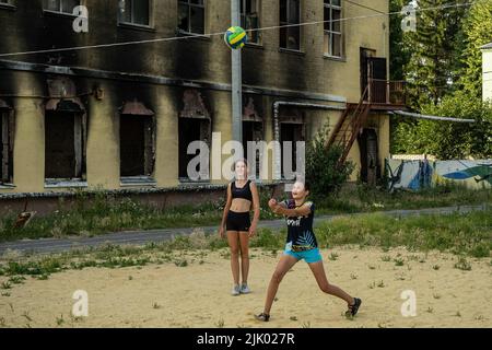 Une famille joue au volley-ball à côté des ruines d'une école à Kharkiv. Kharkiv est la deuxième plus grande ville d'Ukraine, a été l'une des principales cibles stratégiques de l'invasion russe, et depuis le début de la guerre, la ville a subi de multiples attaques de missiles, comme les responsables ont désigné la ville comme la « ville Hero d'Ukraine ». Banque D'Images
