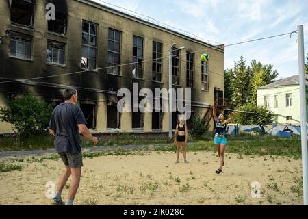 Une famille joue au volley-ball à côté des ruines d'une école à Kharkiv. Kharkiv est la deuxième plus grande ville d'Ukraine, a été l'une des principales cibles stratégiques de l'invasion russe, et depuis le début de la guerre, la ville a subi de multiples attaques de missiles, comme les responsables ont désigné la ville comme la « ville Hero d'Ukraine ». Banque D'Images