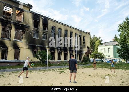 Kharkiv, Ukraine. 8th juillet 2022. Une famille joue au volley-ball à côté des ruines d'une école à Kharkiv. Kharkiv est la deuxième plus grande ville d'Ukraine, a été l'une des principales cibles stratégiques de l'invasion russe, et depuis le début de la guerre, la ville a subi de multiples attaques de missiles, comme les responsables ont désigné la ville comme la « ville Hero d'Ukraine » (Credit image: © Alex Chan TSZ Yuk/SOPA Images via ZUMA Press Wire) Banque D'Images
