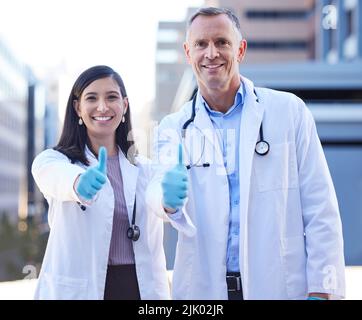 Ensemble, bien prendre une respiration c'est vrai. Portrait de deux médecins montrant les pouces dehors dans la ville. Banque D'Images