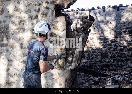 Un pompier frappe un pilier en bois charré. Un incendie a détruit une grande partie des Juniper qui relient Santo Domingo de Silos, Santibáñez del Val et Quintanilla del Coco, dans la province de Burgos. Banque D'Images