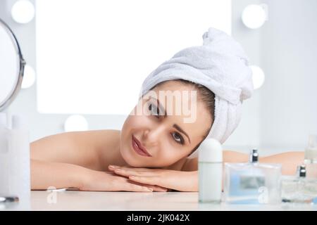 Belle jeune femme avec une serviette sur ses cheveux mouillés regardant l'appareil photo Banque D'Images