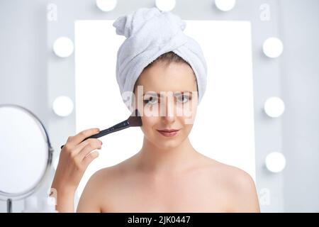 Magnifique jeune femme appliquant le maquillage le matin Banque D'Images