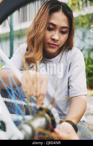 Cycliste vietnamienne fixant la chaîne sur son vélo Banque D'Images