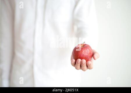 Pomme rouge mûre à la main du jeune homme Banque D'Images