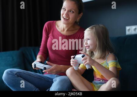 Mère et enfant fille jouant aux jeux vidéo Banque D'Images