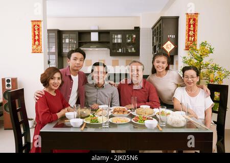 Bonne grande famille vietnamienne pour un dîner de fête. Défile en souhaitant la chance et la richesse en arrière-plan Banque D'Images