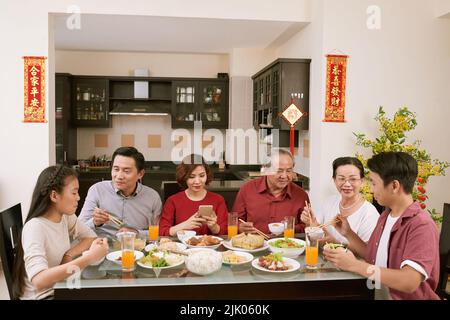 Grande famille asiatique appréciant un grand dîner pour la fête du nouvel an. Défile en souhaitant la chance et la richesse en arrière-plan Banque D'Images