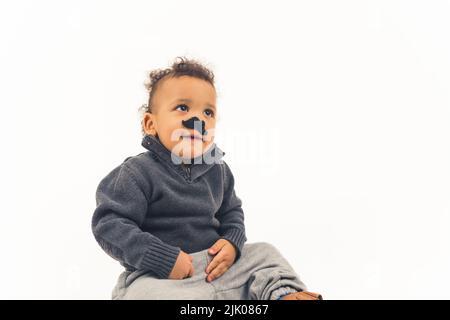 un drôle petit garçon afro-américain avec une moustache artificielle assise sur le sol - isolé en gros plan. Photo de haute qualité Banque D'Images