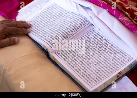 Guru Granth Sahib Sainte écriture religieuse du Sikhisme. La langue pendjabi est écrite sur des pages blanches religieuses lors de la cérémonie de mariage. Banque D'Images