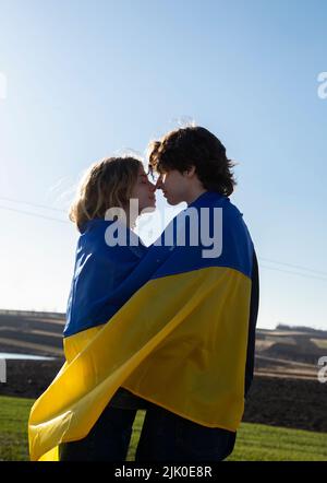 Jeune couple amoureux, gars et fille, en face l'un de l'autre, sont enveloppés dans le drapeau de l'Ukraine. Jour de l'indépendance. Ukraine concept d'amour. Liberté et paix pour Banque D'Images