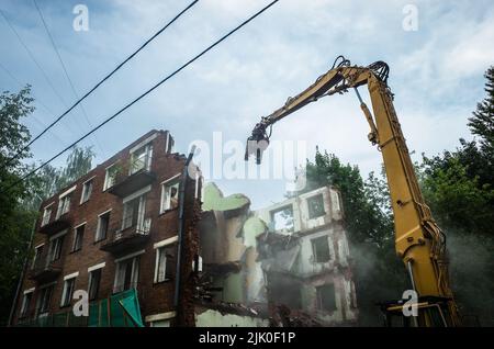 Démolition d'un bâtiment en briques avec bras mécanique de pelle hydraulique. Destruction de logements délabrés. Équipement de construction hydraulique de machines lourdes Banque D'Images