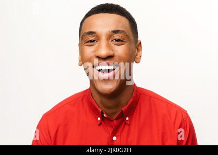 Portrait d'un jeune homme beau et heureux satisfait en chemise debout et regardant l'appareil photo avec un grand sourire. Studio d'intérieur tourné sur fond blanc Banque D'Images