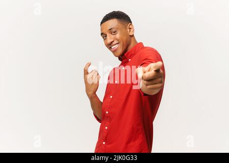 L'homme latin surjoyeux danse, fait des mouvements à la musique, sourit positivement, étant dans l'esprit élevé. Un homme hispanique insouciant dans des danses de chemise rouge isolé sur blanc Banque D'Images