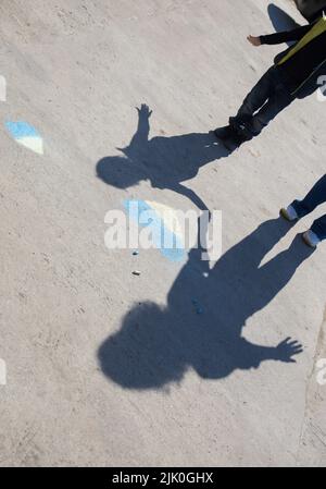 ombres contrastées sur le trottoir de deux personnes, femme et enfant près de coeur jaune-bleu dessiné dans des crayons. Les Ukrainiens veulent la paix. Enfance pendant la guerre Banque D'Images