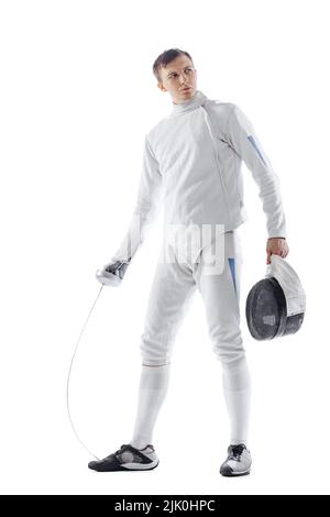 Portrait d'un tireur professionnel en costume d'escrime et masque tenant une petite épée isolée sur fond blanc. Sport, émotions, énergie, compétences Banque D'Images