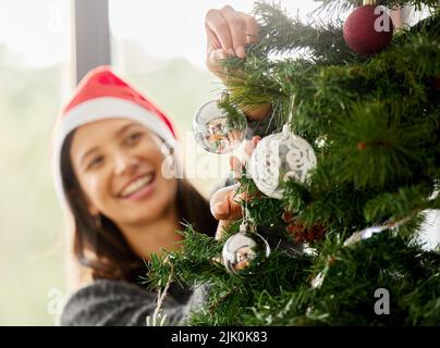 Une belle chose au sujet de Noël est que son obligatoire. Une jeune femme portant un chapeau de Noël à la maison. Banque D'Images