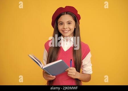 bonne adolescente en béret français, en train de faire des notes dans le bloc-notes ou le bloc-notes de l'agenda, l'école Banque D'Images