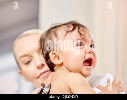 Je ne pense pas que j'aime ce médecin. Un petit bébé pleure en étant examiné par un médecin. Banque D'Images