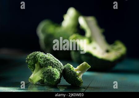 Bouquets de brocoli, avec le brocoli entier et moitié en arrière-plan Banque D'Images